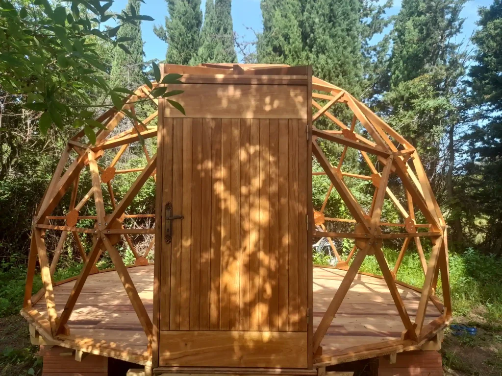 View of the door and structure of a wooden geodesic dome being assembled